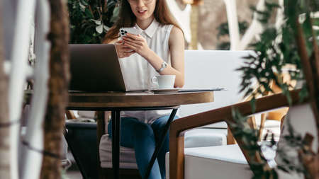 young business woman with a smartphone taking notes in her notebook.の写真素材