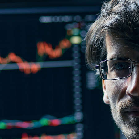 young investor yawns and looks at the screens with the charts of the stock market of...