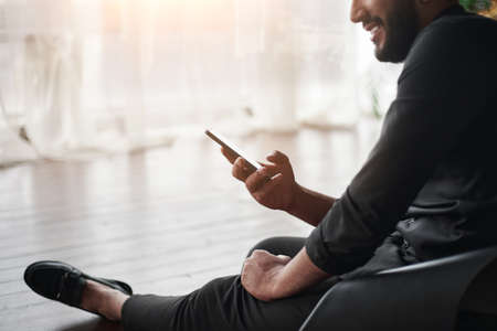 cropped image of a businessman with a smartphone sitting in his new office.
