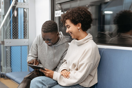 young couple using a digital tablet while sitting in a subway car.の写真素材