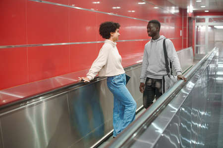 couple of students are talking standing on the escalator in the