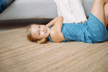 little girl is playing lying on the floor in the living room .の写真素材