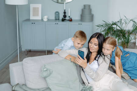 mom with two kids watching videos on her smartphone.の写真素材