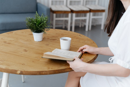 woman reading a book sitting at a coffee table.の写真素材