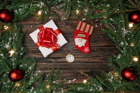 clock, Christmas stocking and a gift on a wooden background.