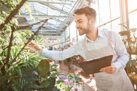 cheerful florist checking the assortment in his flower shop.の写真素材