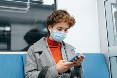 young woman using her smartphone while sitting in a subway car.の写真素材