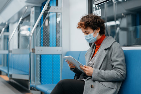 young woman with an e-book sitting in a subway car.の写真素材
