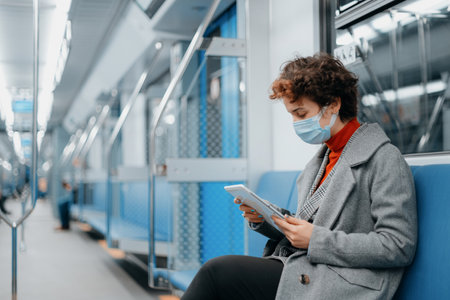 young woman with an e-book sitting in a subway car.の写真素材