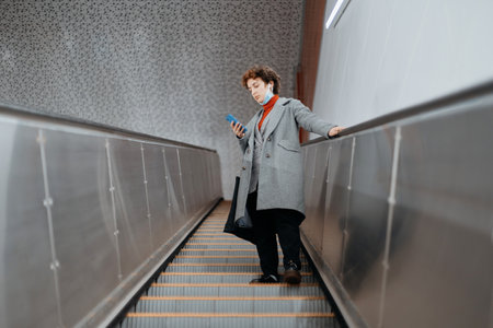 woman with a smartphone standing on the escalator steps.の写真素材