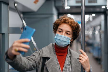 young woman talking on her smartphone in a subway car.の写真素材