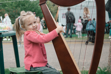 little girl with a harp on the lawn in the city Park.の写真素材