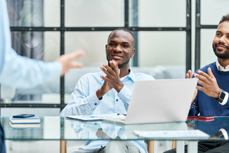 business team applauding their colleague sitting at the desk.の写真素材