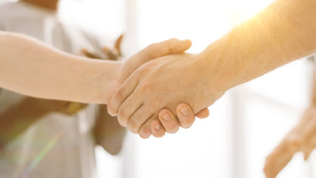 close up. two comrades shaking hands, standing in a circle of friendsの写真素材