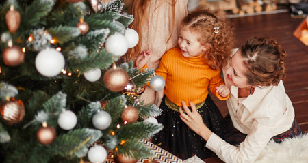 mom and her little daughters decorating the Christmas treeの写真素材