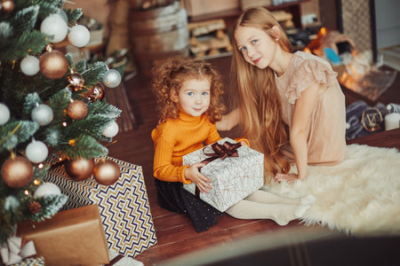 two pretty sisters sitting on the floor on Christmas eveの写真素材