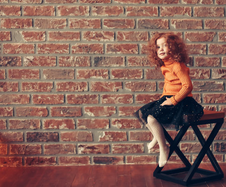 cute little girl sitting on a chair in a new living room.の写真素材