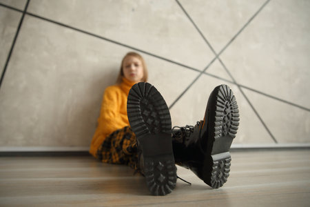 girl in a yellow sweater sitting near the wall.の写真素材
