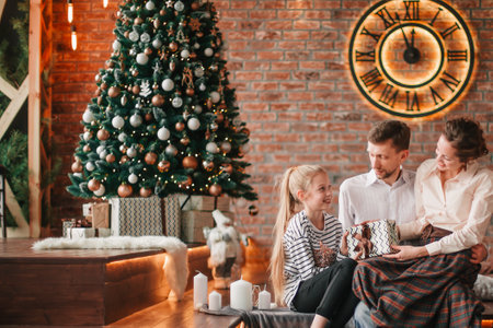 parents with their young children sitting in the living room decorated for Christmasの写真素材