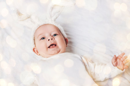 close up. smiling baby in a rabbit suit. beautiful bokeh effect from a garlandの写真素材