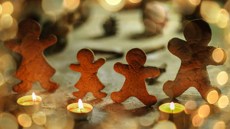 candles and gingerbread men at the Christmas table. beautiful bokeh effect from a garland.の写真素材