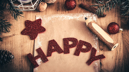 greeting card,pencil,candle and Christmas decoration on wooden background. happy inscription on the holiday sheet.の写真素材