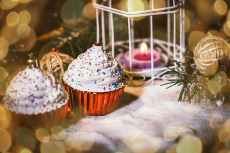 cupcakes,Christmas candle and Christmas decorations on wooden background. beautiful bokeh effect from a garland.の写真素材