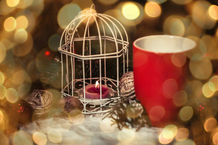 closeup.red Cup and candle at the Christmas holiday table. beautiful bokeh effect from a garland.の写真素材