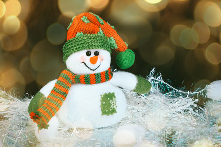 Toy decorated with a snowman, in the black background. beautiful bokeh effect from a garland.の写真素材