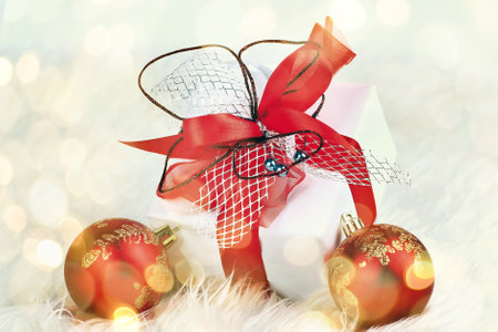 Christmas. holiday gift in a beautiful package and red glass balls on festive background. beautiful bokeh effect from a garland.の写真素材