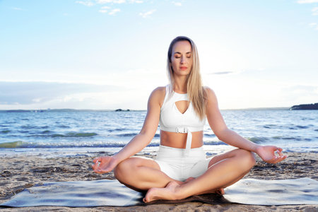 attractive woman practicing yoga by the lake.の写真素材