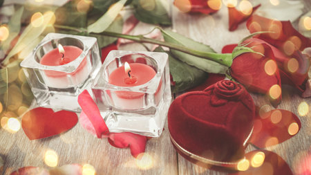 ring in the box and rose on a light wooden background. Beautiful bokeh effect from a garland.の写真素材