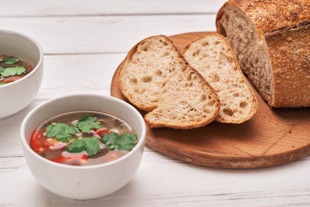 wholegrain bread and a bowl of soup on a wooden background.の写真素材