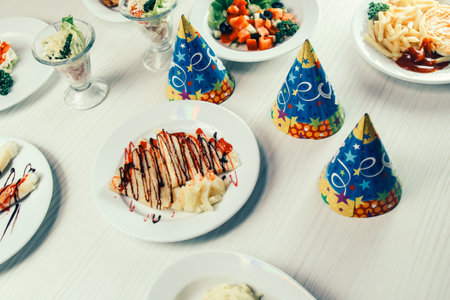 festive caps and a variety of dishes on the table in the childrens restaurantの写真素材