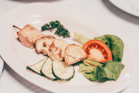 kebab on a wooden skewer and other dishes for a family dinner in the restaurantの写真素材