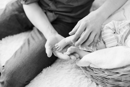 father holding the legs of his newborn son. close-up. black and white photo