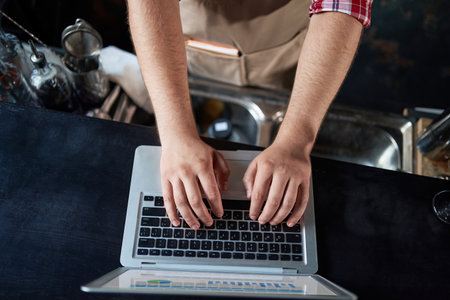 cropped image of a male bartender using a laptop.の写真素材