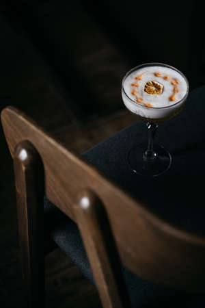 White cocktail with caramelized orange on dark blue chair.の写真素材