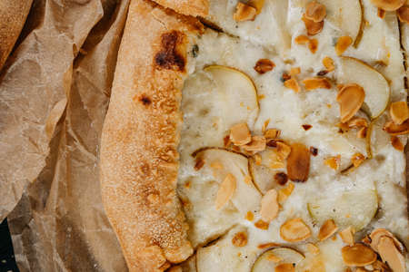 Close up pizza slice with pear gorgonzola and almond served on parchment paperの写真素材