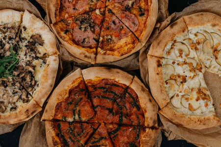 Four different pizza served on parchment paper. Meat and vegetarian.の写真素材