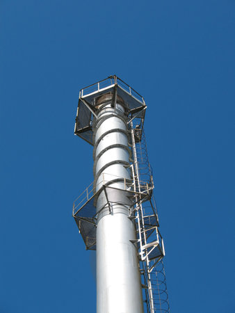 The factory chimney photographed on a background of the blue sky