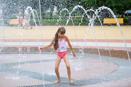 The girl bathes in a fountain in hot dayの写真素材