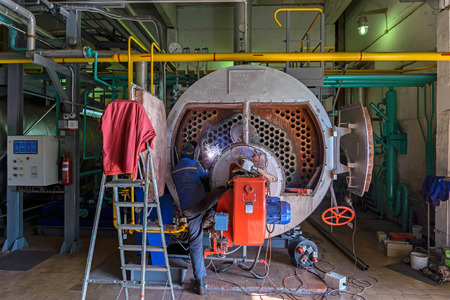 Worker repairing the boiler with the aid of welding