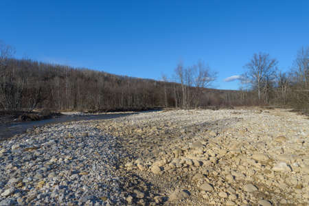The coast of the mountain river, strewn with pebbles .