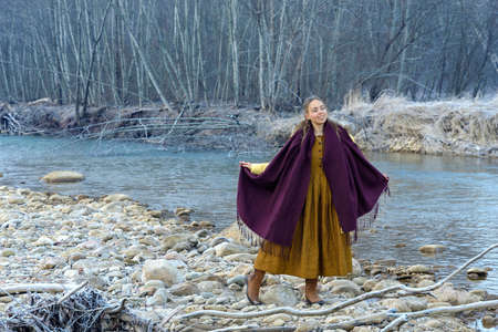 Model posing against the backdrop of a mountain riverの写真素材