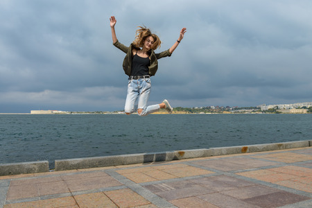 Young girl in a jump shot against the seaの写真素材