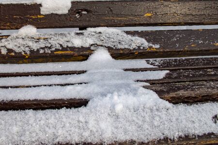 Old brown wooden bench in the Park, covered with snowの写真素材