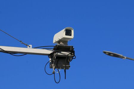 Video surveillance camera mounted on a pole above the city street. Security, control.