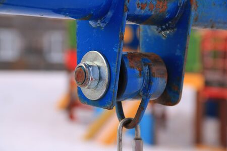 The suspension device of a children's swing close-up. Metal with peeling paint, carabiner for fastening the seat.の写真素材
