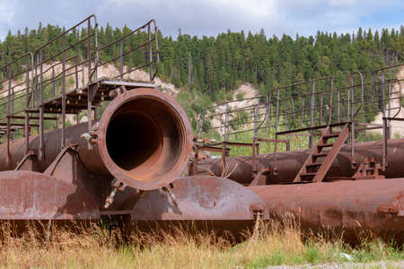 The huge rusty pipes on the pontoons are parts of the sand washing mechanism. Stand on the bank overgrown with grassの写真素材